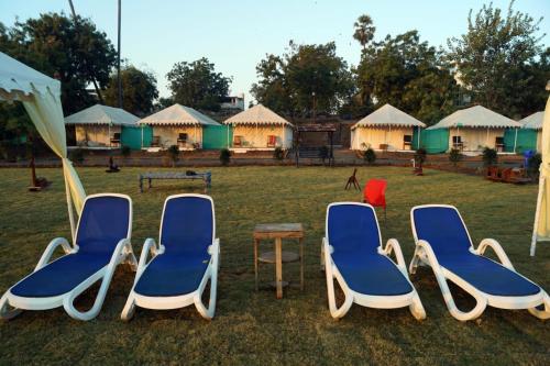a group of chairs and a table and some huts at River View Tent Resort in Garudeshwar