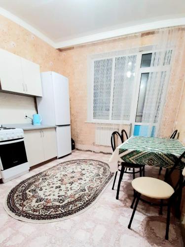 eine Küche mit einem Tisch, einem Tisch und Stühlen in der Unterkunft Однокомнатная квартира в ЖК Сенатор, рядом с посольством США in Astana