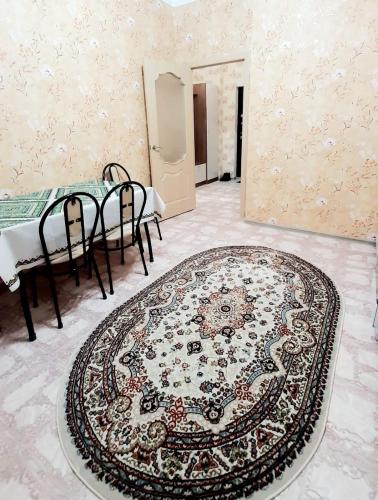 Zimmer mit einem Teppich auf dem Boden und einem Tisch mit Stühlen in der Unterkunft Однокомнатная квартира в ЖК Сенатор, рядом с посольством США in Astana