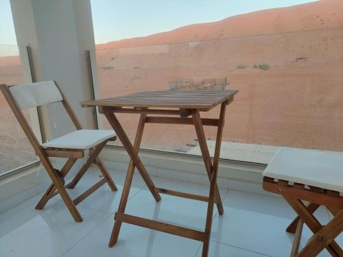 Al Raka的住宿－شاليهات رمال بديه，一张木桌和一张靠窗的椅子