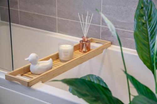 a wooden shelf in a bathroom with candles and a plant at Modern 3 bedroom spacious house with parking in Bath