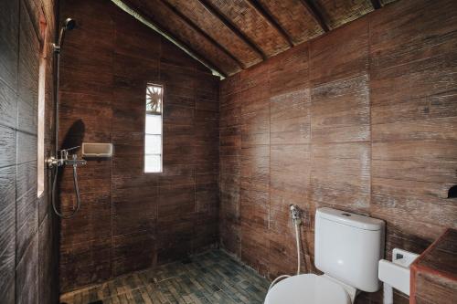 baño con aseo y paredes de madera en Tunjung Sari Villa Bedugul, en Bedugul