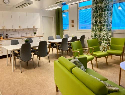 einen Konferenzraum mit grünen Stühlen und Tischen sowie eine Küche in der Unterkunft Kuttainen Lodge in Karesuando