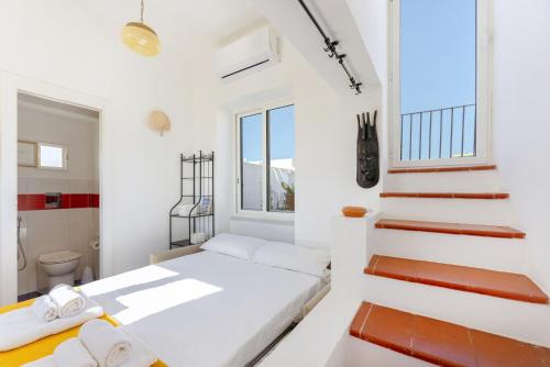 a white bedroom with a bed and a bathroom at TORRETTA CORRICELLA- Torretta in Procida