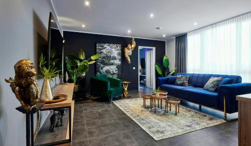 ein Wohnzimmer mit einem blauen Sofa und einigen Pflanzen in der Unterkunft MARRAM Suitehotel in Münster