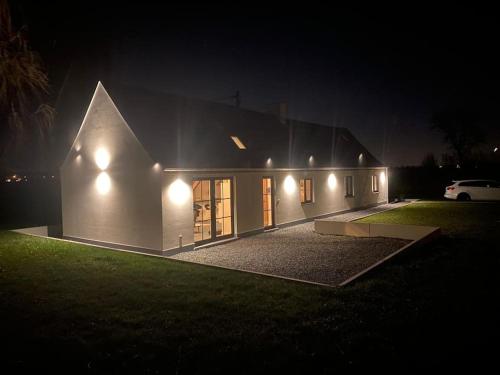 una casa con luces al costado de ella por la noche en Cosy Cott, een verborgen logeerplek in het landelijke Poeke., en Aalter