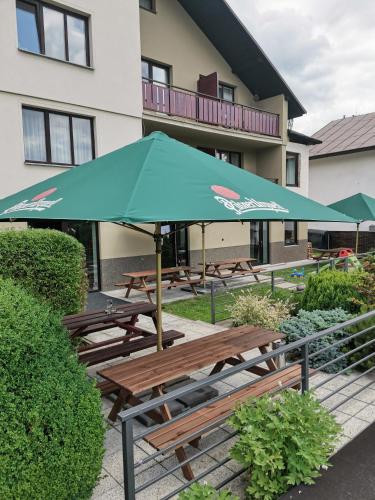 a group of picnic tables with a blue umbrella at Penzion Garden in Cerny Dul
