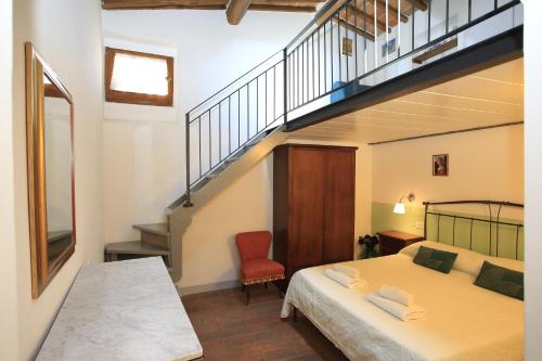 Fabio Apartments San Gimignano في سان جيمنيانو: غرفة نوم بسرير ودرج