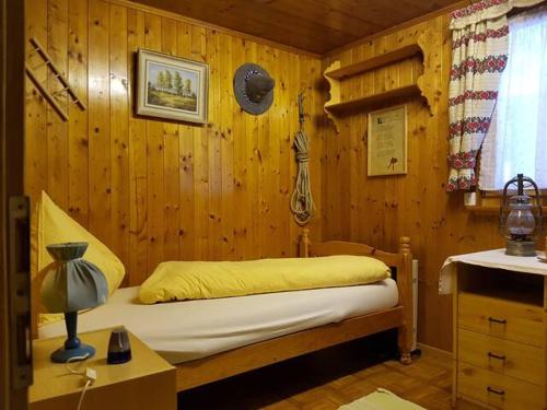 1 dormitorio con 1 cama en una pared de madera en Zimmer für Backpaking - Das gemütliche Haus des Grossvaters - Bergheimat - Ganz einfach - ganz unkompliziert - ganz relaxd, en Linthal