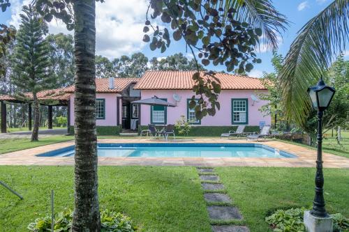 a villa with a swimming pool and a house at Sítio Paraíso Beach Tennis in Vassouras