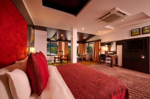 1 dormitorio con 1 cama grande con almohadas rojas en Renest River Country Resort Manali, en Manali