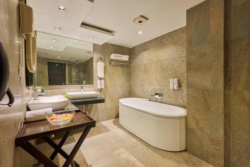 a bathroom with a tub and a sink and a toilet at Renest River Country Resort Manali in Manāli