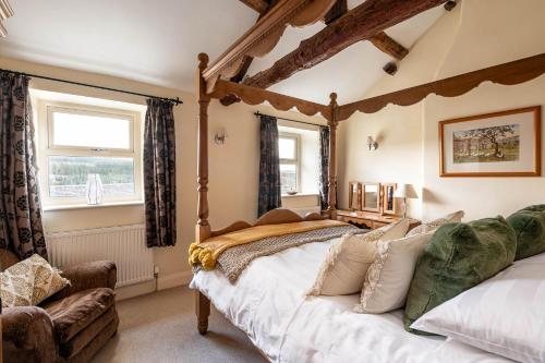um quarto com uma cama grande e uma cadeira em Bilberry Bank Cottage em Holmfirth