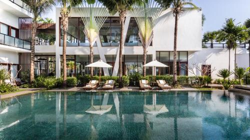 a swimming pool in front of a building with palm trees at Anansaya La Maison in Siem Reap