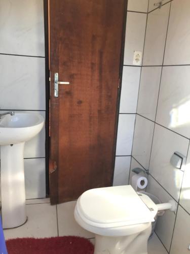 baño con aseo y lavabo y puerta de madera en Pousada Catarinense, en Chapada dos Guimarães