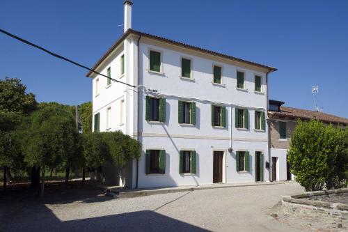 a large white building with green shuttered windows at Casa Sincielli in Caorle