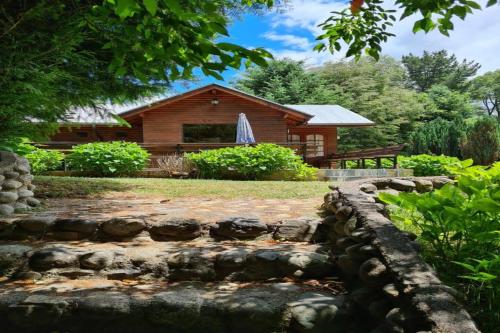 Cabaña de madera con un camino de piedra frente a una casa en Orillas del Coilaco en Pucón