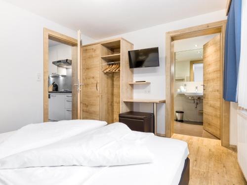 a bedroom with a white bed and a kitchen at Apart Corona in Sölden