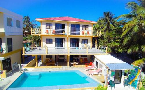 una casa grande con piscina frente a ella en Beach Club Budget Rooms at Popeyes Caye Caulker en Caye Caulker