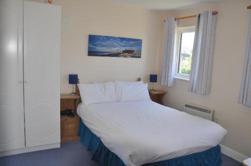 1 dormitorio con 1 cama grande y ventana en Ardamine Holiday Homes en Courtown