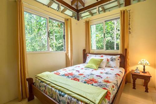 1 dormitorio con 1 cama y 2 ventanas en Peace Garden Spacious Bungalows- a walk to the beach, en Cocles