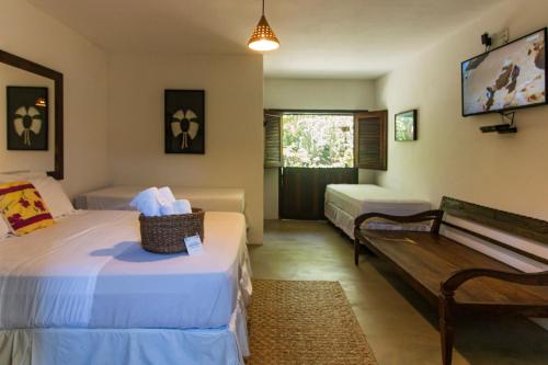 a hotel room with two beds and a bench at Pousada Nativa in Caraíva