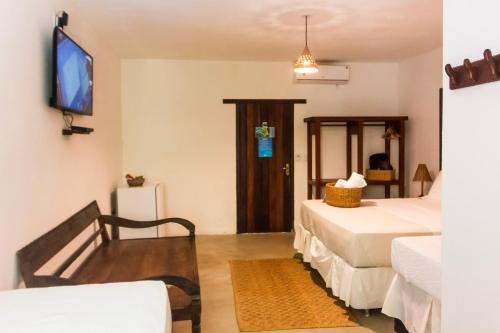 a hotel room with two beds and a tv at Pousada Nativa in Caraíva