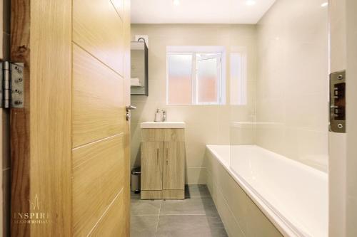 a bathroom with a bath tub and a sink at Broomsleigh NW6 Apartment in London