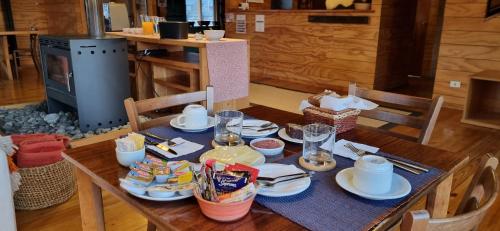 Una mesa de madera con platos de comida encima. en Rumbo Sur Hotel, en Villa O'Higgins