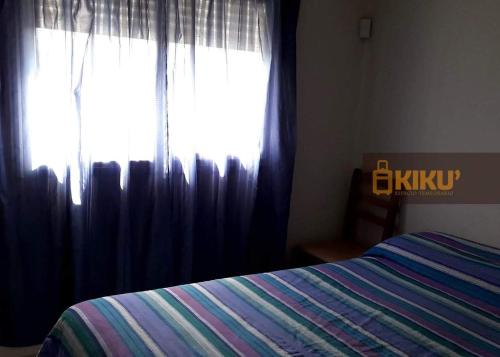 1 dormitorio con 1 cama y una ventana con cortinas en Departamento Kiku barrio cerrado Villasol con pileta en Córdoba