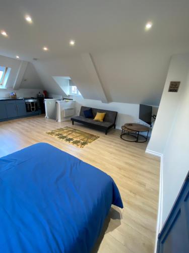 a bedroom with a blue bed and a couch at Lovely spacious loft close to train station in Worthing