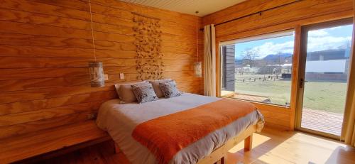 sypialnia z łóżkiem i dużym oknem w obiekcie Rumbo Sur Hotel w mieście Villa O'Higgins