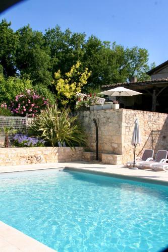 une piscine avec deux chaises et un parasol dans l'établissement Maison d'hôtes De La Boissière, à Andillac