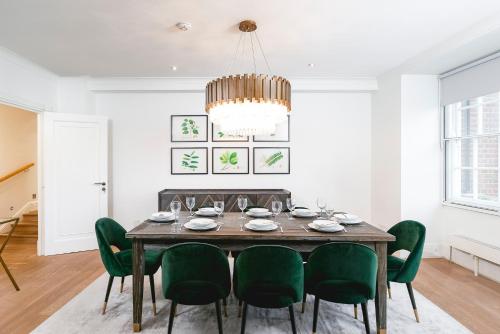 een eetkamer met een tafel en groene stoelen bij ' Luxury & Spacious 4 Bed 4 Bath Apartment ' in Londen