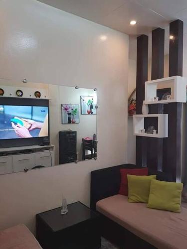 Entire House - Daet (Fully Furnished) في Daet: غرفة معيشة مع أريكة وتلفزيون بشاشة مسطحة