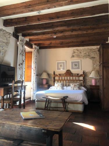a bedroom with a large bed and a table at Posada Real Mingaseda in Navafría