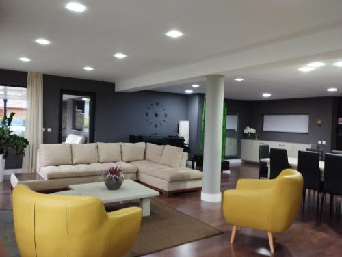 a living room with a white couch and yellow chairs at Vila Gosen in Şard