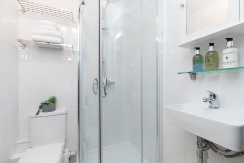 a white bathroom with a shower and a sink at Modern Self Contained Studio Home in Cheltenham