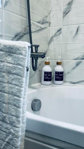 two bottles ofodorizers sitting on the edge of a bath tub at Nathallie Modern Apartments in Timişoara