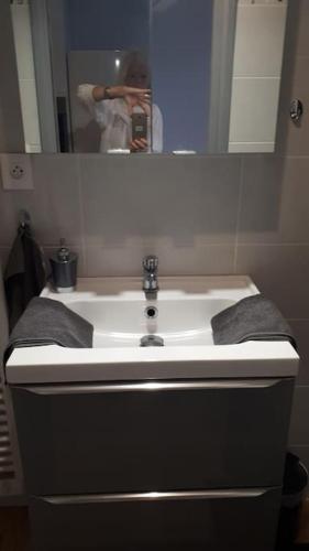 une personne prenant une photo d'un lavabo dans la salle de bains dans l'établissement Marcailhou, à Ax-les-Thermes