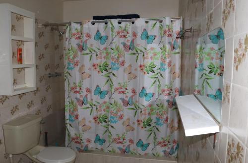uma casa de banho com uma cortina de chuveiro com borboletas em Dover Beach House em Christ Church