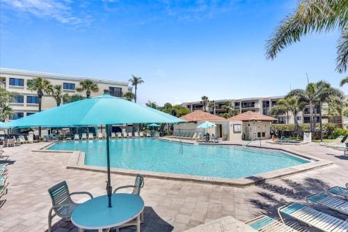 a table with an umbrella next to a swimming pool at Land's End 3-404 Bay Front in St Pete Beach