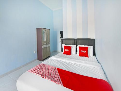 OYO Life 91399 Homestay Trendy Syariah في سيلاكاب: غرفة نوم مع سرير مع وسادتين حمراء