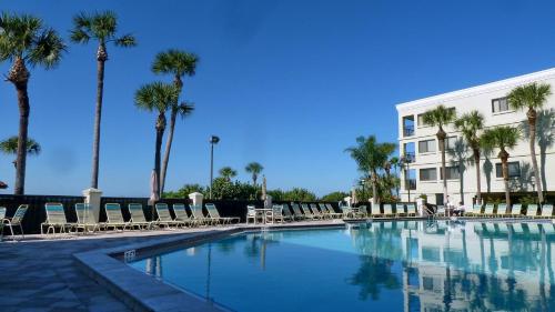 a swimming pool with chairs and palm trees and a building at Land's End 8-401 Beach Front in St. Pete Beach