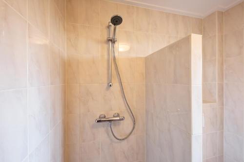 een douche met een douchekop in de badkamer bij De Leeuwerik in De Koog