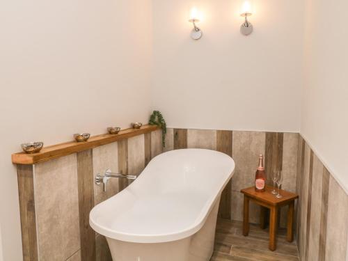 a bathtub in a bathroom with a wooden wall at Bracken Cottage in York
