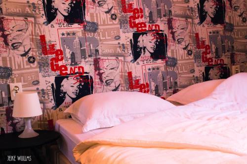 Un dormitorio con una cama y una pared cubierta de carteles. en De Roermondse beleving en Roermond