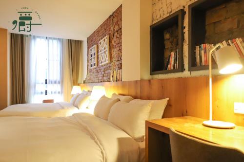 a hotel room with two beds and a desk at Roots Chew Hotel in Tainan
