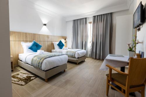 a hotel room with two beds and a desk at Karam City Hotel in Dakhla