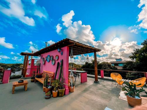 a pink house with plants and chairs on a deck at Vila Real Apartamentos in Itacaré